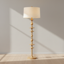 A tall floor lamp with a natural wood spindle-style base and a large cream fabric drum shade, shown against a plain white background.