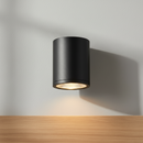 A modern black cylindrical recessed ceiling light with a textured glass diffuser and a warm glowing light inside, shown against a plain white background.